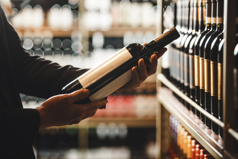 Osoba trzymająca butelkę z winem